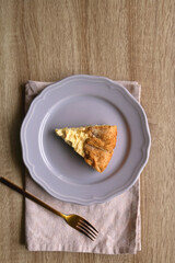 Slice of cheese and leek quiche on wooden table. Flat lay.