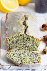 Lemon cake with poppy seeds, covered with glaze on a light background.
