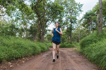 Active young Asian woman running at tropical forest trail. Female runner trail running in the forest. Healthy lifestyle. © ME Image