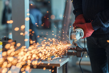 Worker working with a circular grinder on a metal with sparks flying out of them, selective focus