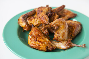 Delicious grilled fried quails lie on a green plate. Delicious and healthy meat.