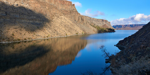 Reflection of the blue sky in the water of Deschutes River in the rocky canyon in central Oregon.