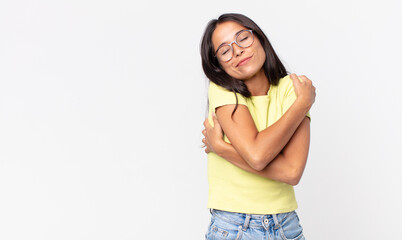 pretty thin hispanic woman feeling in love, smiling, cuddling and hugging self