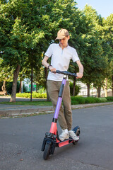 A young man rides an rented electric scooter in the park