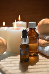 Obraz na płótnie Canvas Autumn spa aromatherapy composition with essential oil bottles, bath bombs and lit candles on wooden background. Bath cosmetic products treatment. Wellness. Massage. Relax. Trendy fall still life.