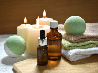Spa aromatherapy still life with bath bombs, essential oil bottles and lit candles on wooden background. Natural cosmetic products treatment. Wellness. Massage. Trendy still life for resort, salon.