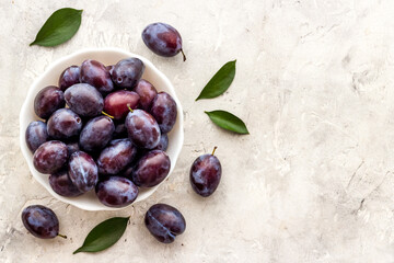Food layout with plums in bowl with leaves. Top view