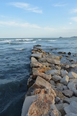 Rocky path into the mediterranean sea with Peñiscola's castle in the background and a blue perfect sky.