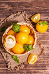 Ripe yellow tomatoes with fresh basil in a wicker basket
