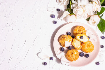 Fototapeta na wymiar Profiteroles with blueberries. Custard cakes, Eclair, cream puff on a wooden stand