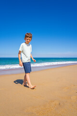 Happy boy walking and playing on the summer beach. Young teenager relax and having fun in summer holiday vacation travel.