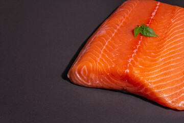 Fresh raw salmon or trout sea fish fillet on black stone background