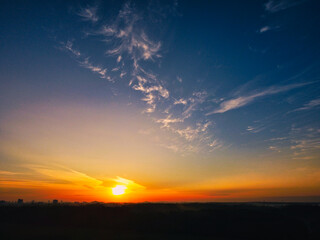 sunrise over a field in Germany with forest and cityline in background