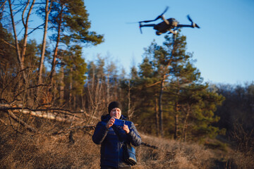 Adult man preparing to taking photo or video of nature landscape. Male photographer holding smartphone and controls the drone