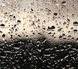 Water drops reflecting on a window during a heavy rain storm on a dark afternoon