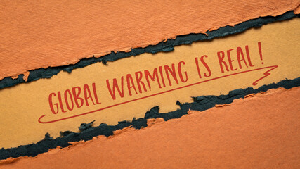 global warming is real - climate emergency concept, handwriting on a handmade orange and black paper
