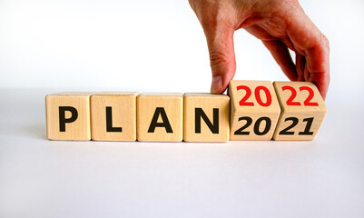 2022 plan new year symbol. Businessman turns a wooden cube and changes words 'Plan 2021' to 'Plan 2022'. Beautiful white background, copy space. Business, 2022 plan new year concept.