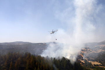 Fototapeta na wymiar fire fighting helicopter leaves water to the forest fire