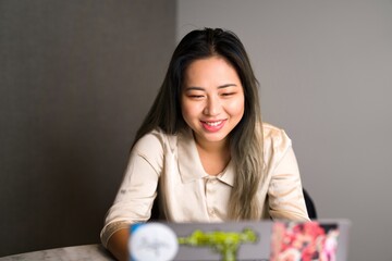 Smiling Young Edgy Female Asian Data Scientist on a Video Conference Using Her Laptop | Office Conference Room