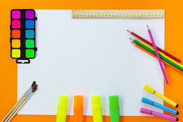 Back to school. Education concept. Drawing. Paints, markers, felt tip pens, colored pencils, ruler with white sheet for text on orange background. Copy space