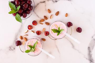 Obraz na płótnie Canvas Top view of two glasses of cherry smoothie with almond and mint. Healthy dieting breakfast.