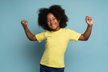 Child sincerely rejoicing success. Cute energetic enthusiastic little girl raising arms in...