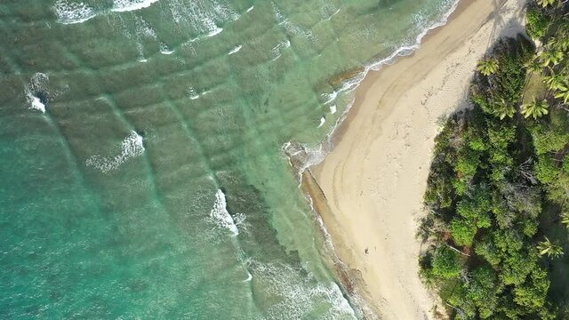 A footage of a sandy beach of an azure ocean viewed from above