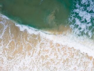 Aerial view high angle view Top-down seawater wave on sandy beach. Aerial view above beach sea in tropical beach sea.