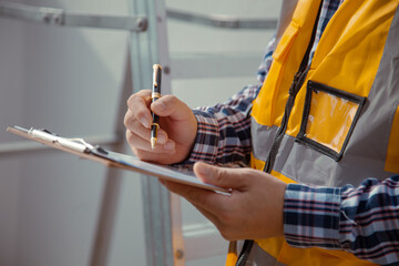 building contractor Check and write down the details of the construction. wearing yellow...