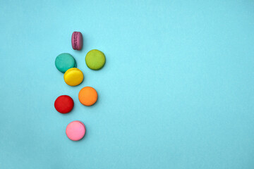 Obraz premium top down composition multicolored sweet dessert macaroni cakes are randomly scattered isolated on a pale blue background with space for text. concept of diet, mother day, delicious junk food 