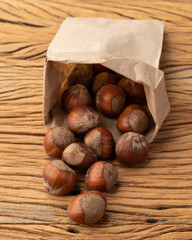 Hazelnuts in a paper bag over wooden table