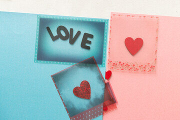 the word "love" in wooden letters on blue and pink construction paper background and a fancy plastic overlay - with red hearts