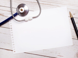 On a light wooden table there is a stethoscope, a pen and a sheet of paper with a place to insert...