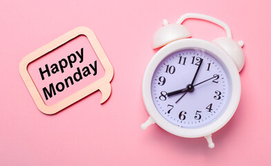 On a delicate pink background, a white alarm clock and a wooden frame with the text HELLO MONDAY