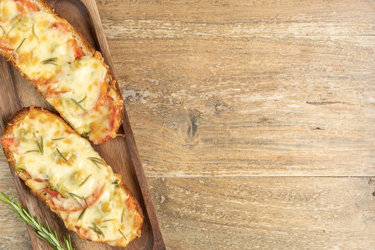 French bread sandwich with cheese, broccoli, tomatoes and rosemary on wooden background with copy space.