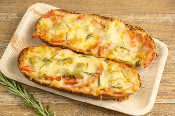 French bread sandwich with cheese, broccoli, tomatoes, rosemary on wooden background.