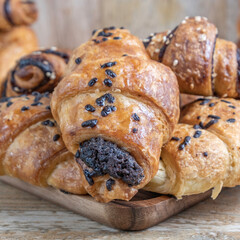 Fresh chocolate croissants on wooden background.