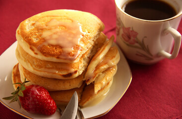 Homemade pancakes with strawberries. Cup of coffee on background.