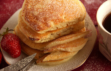 Breakfast with coffee. Fragrant pancakes with powdered sugar, condensed milk and strawberries.