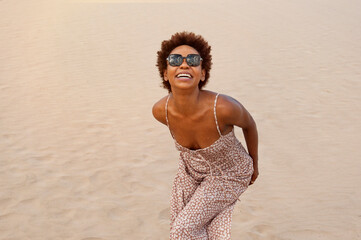 Fototapeta na wymiar Black skinned latin girl with afro smiling in the sand. Happiness, freedom and satisfaction. Concept of latin people