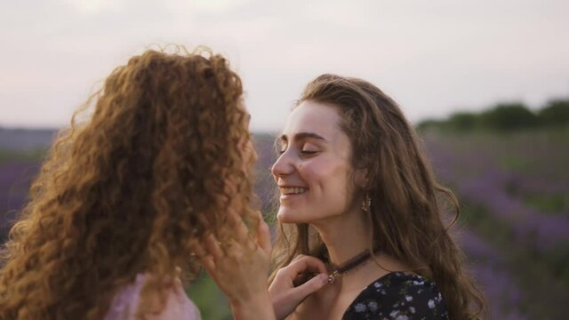 Two sensual women among a lavender field, funny rubbing their noses