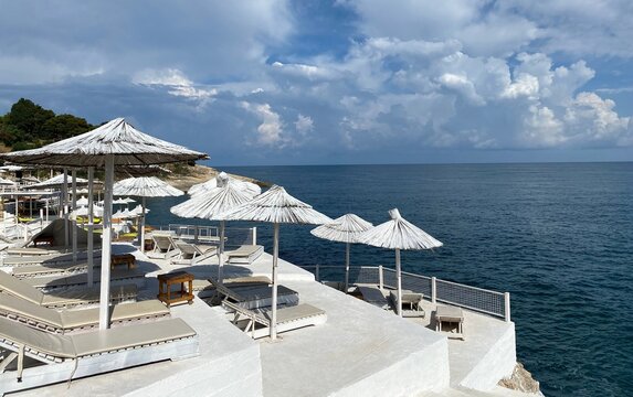 Beach lounge chairs and umbrellas. Beautiful white beach on sea shore at summer day. Sun parasols, loungers against calm water and  blue sky. Wonderful summer. Relaxing holiday on Mediterranean coast.