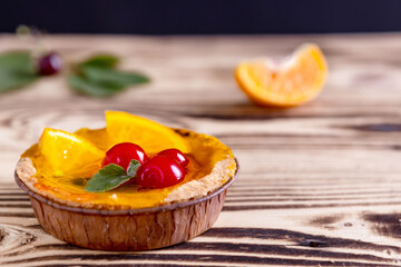 tartlets with tangerine and cherry on a wooden background. home baking, selective focus