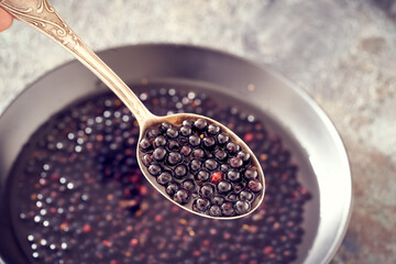 Fresh elderberries on a spoon - preparation of homemade black elder syrup