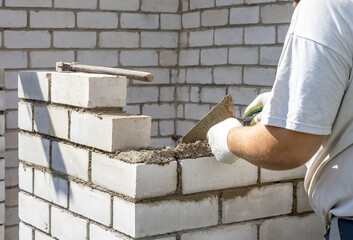 men's hands lay bricks on the reconstruction of the house