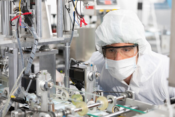male engineers wearing personal protective equipment uniform(PPE) and medical face mask, checking machine in laboratory
