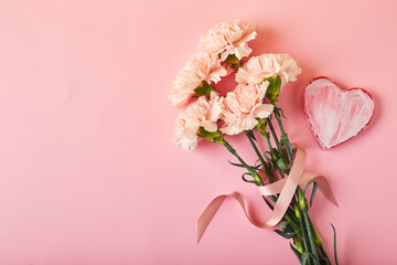 Bouquet of pink carnations. Design concept of holiday greeting with carnation bouquet on pink table background