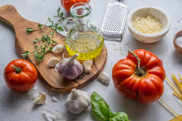Preparing an Italian meal with a chopping board, tomatoes, garlic, oil, basil, cheese and salt