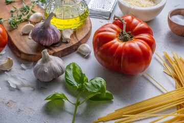 Preparing an Italian meal with a chopping board, tomatoes, garlic, oil, basil, cheese and salt