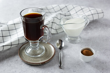 Healthy hot chicory drink in the glass cup , crushed chicory root in small white bowl and milk in glass jug on concrete background. Side view